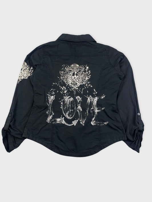 Back view of a long-sleeve blouse in black featuring intricate white graphic print.