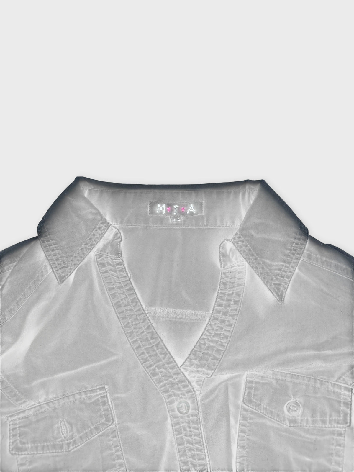 Detail view of a long-sleeve blouse in white with buttoned pockets.