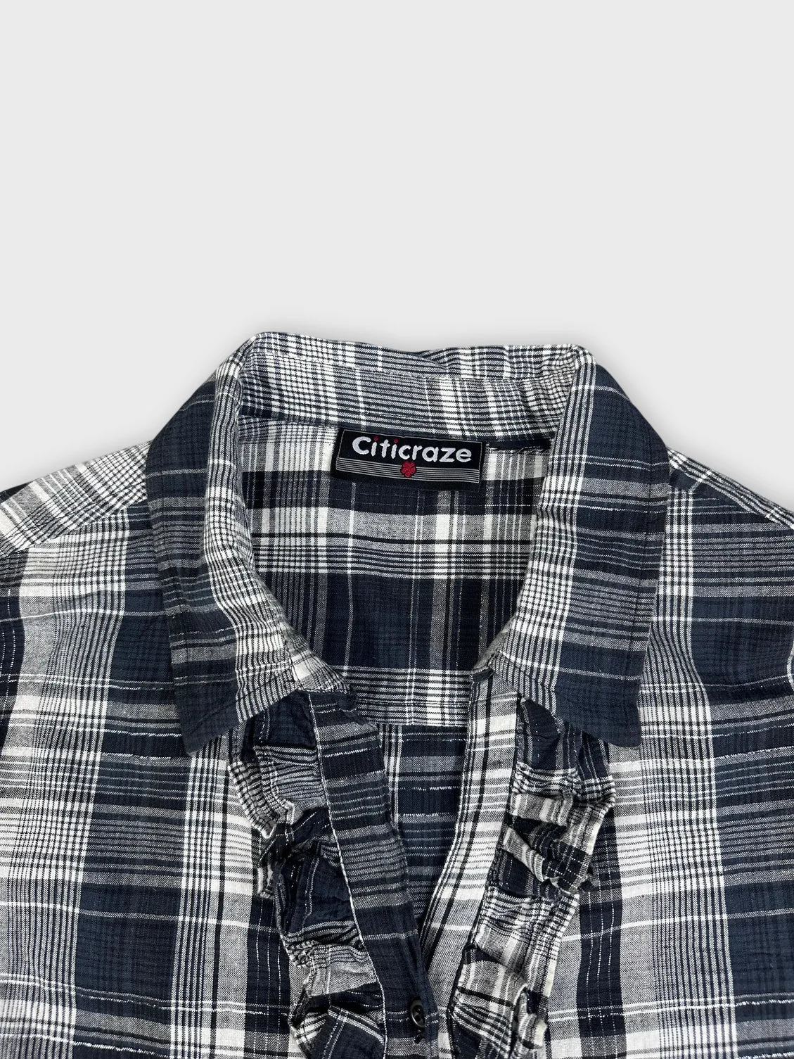 Detail view of a longsleeve top in navy and white plaid pattern.