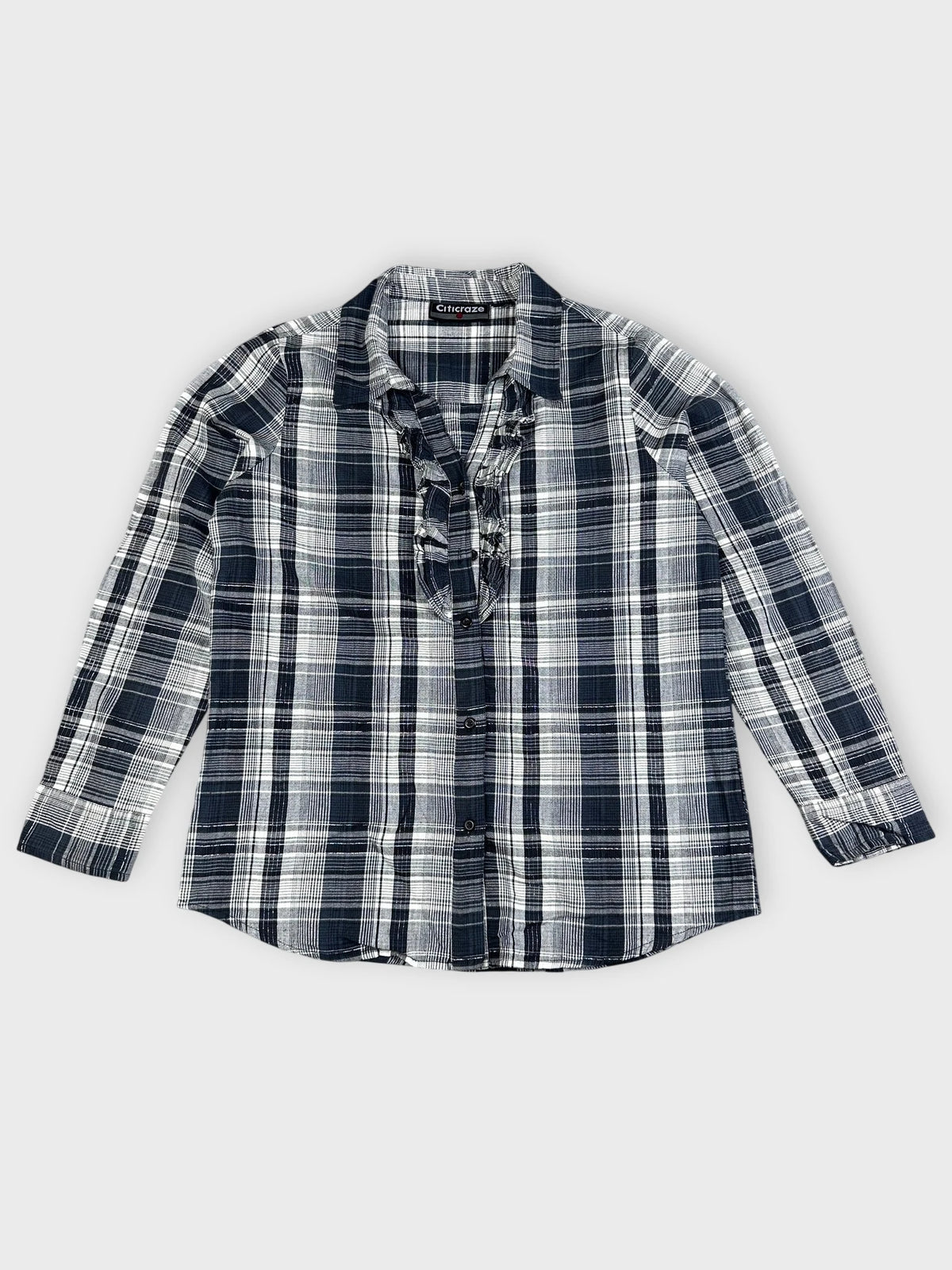 Detail view of a longsleeve top in navy and white plaid pattern.
