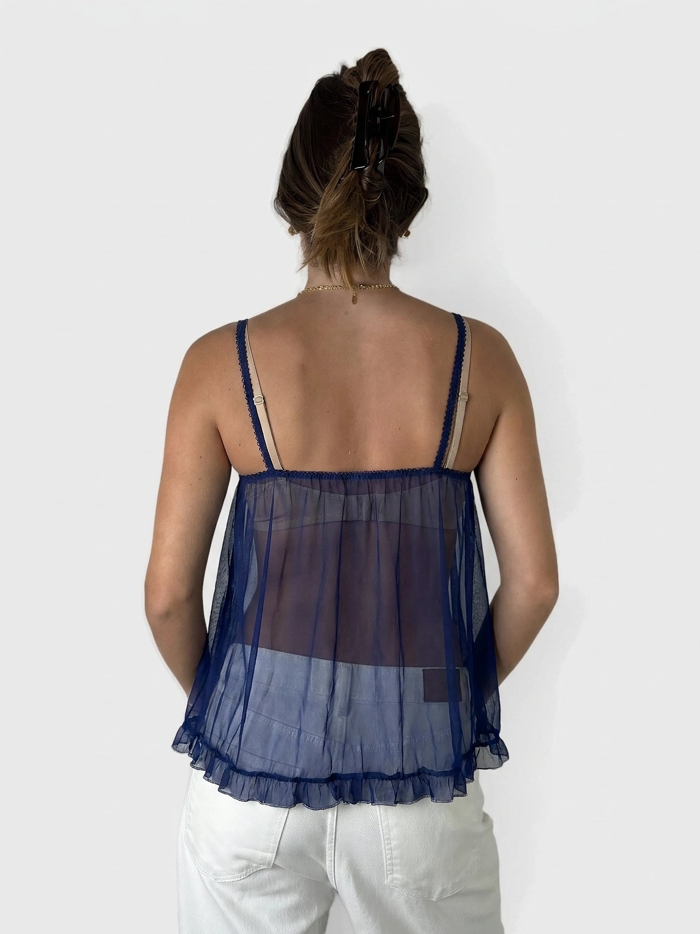 Back view of a navy lace camisole featuring a ruffled hem.