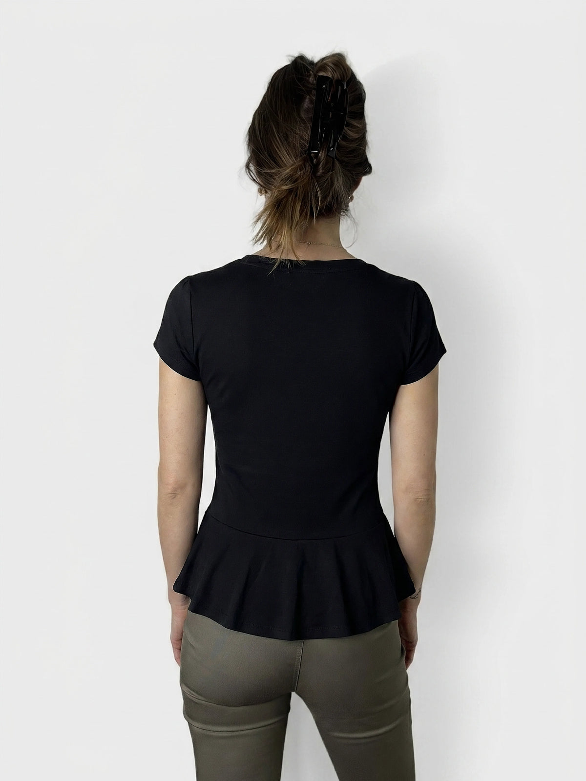 Back view of a navy peplum body shirt with button detail.