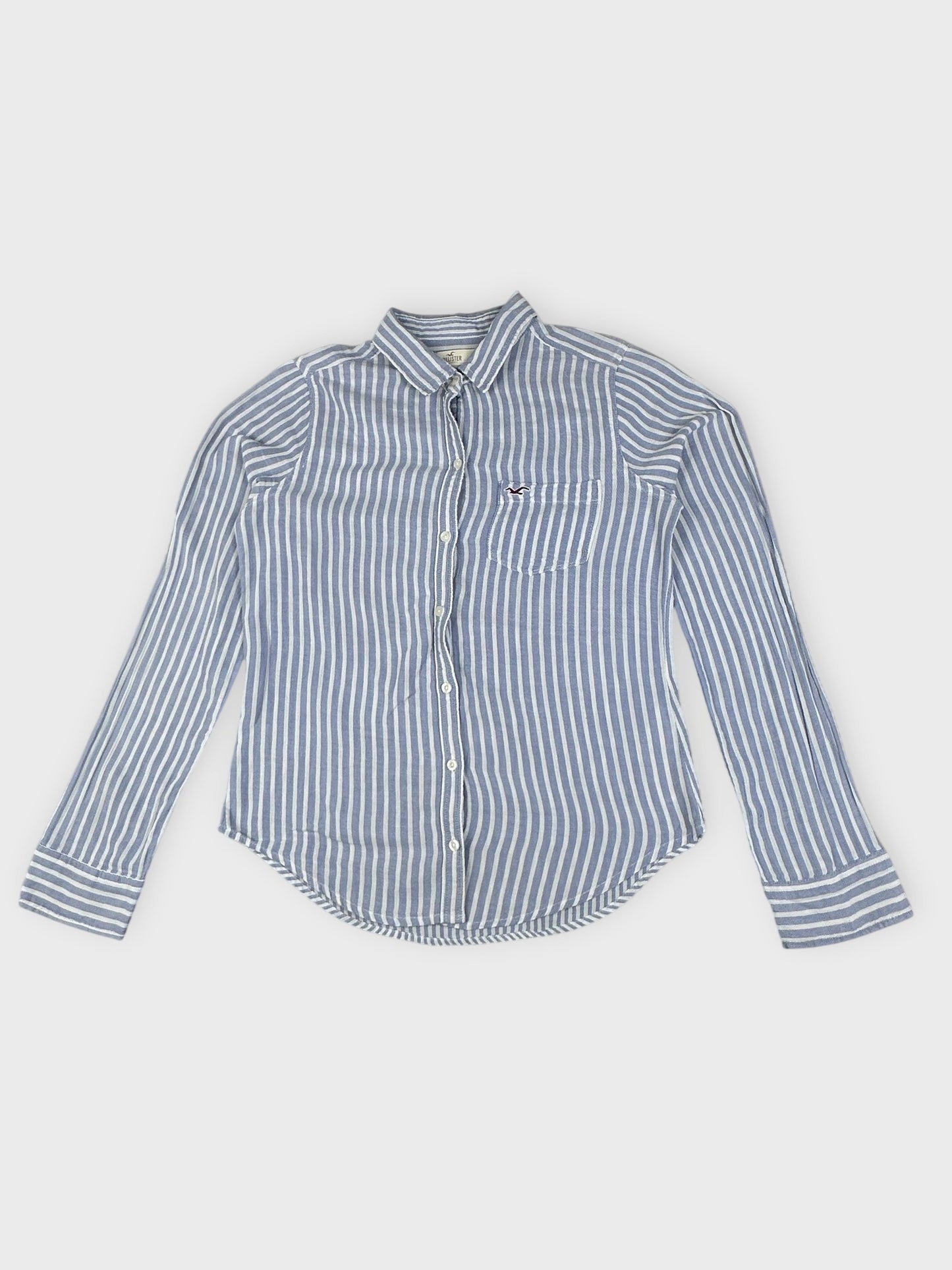 Detail view of a blue and white striped button shirt with a logo pocket.