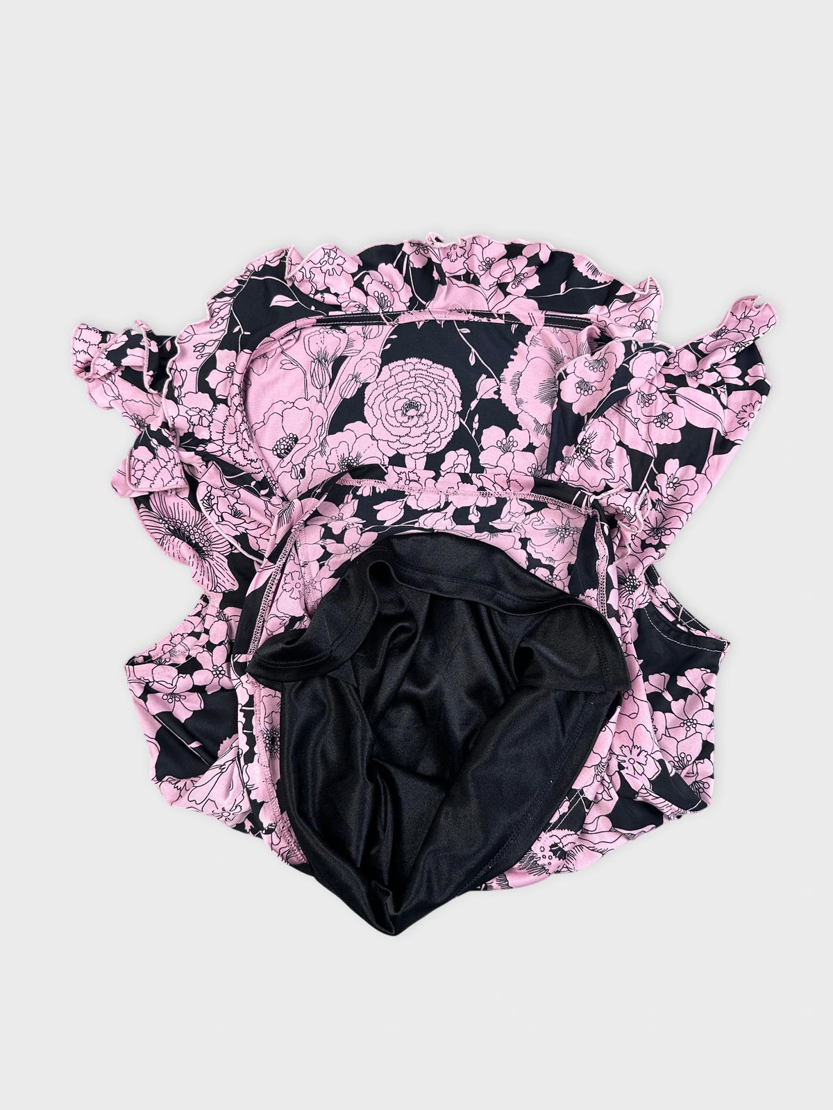 Detail view of a pink floral vintage corset dress with ruffled trim.