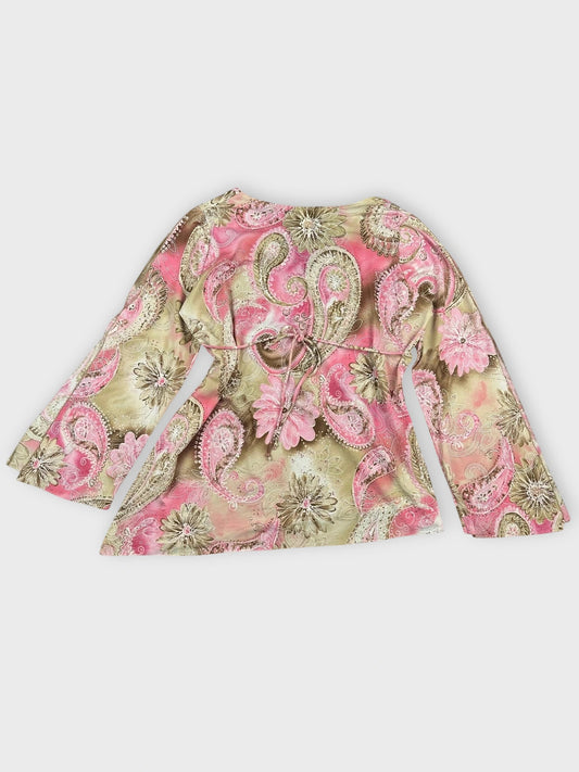 Back view of a pink floral wrap top with bell sleeves and tie belt.