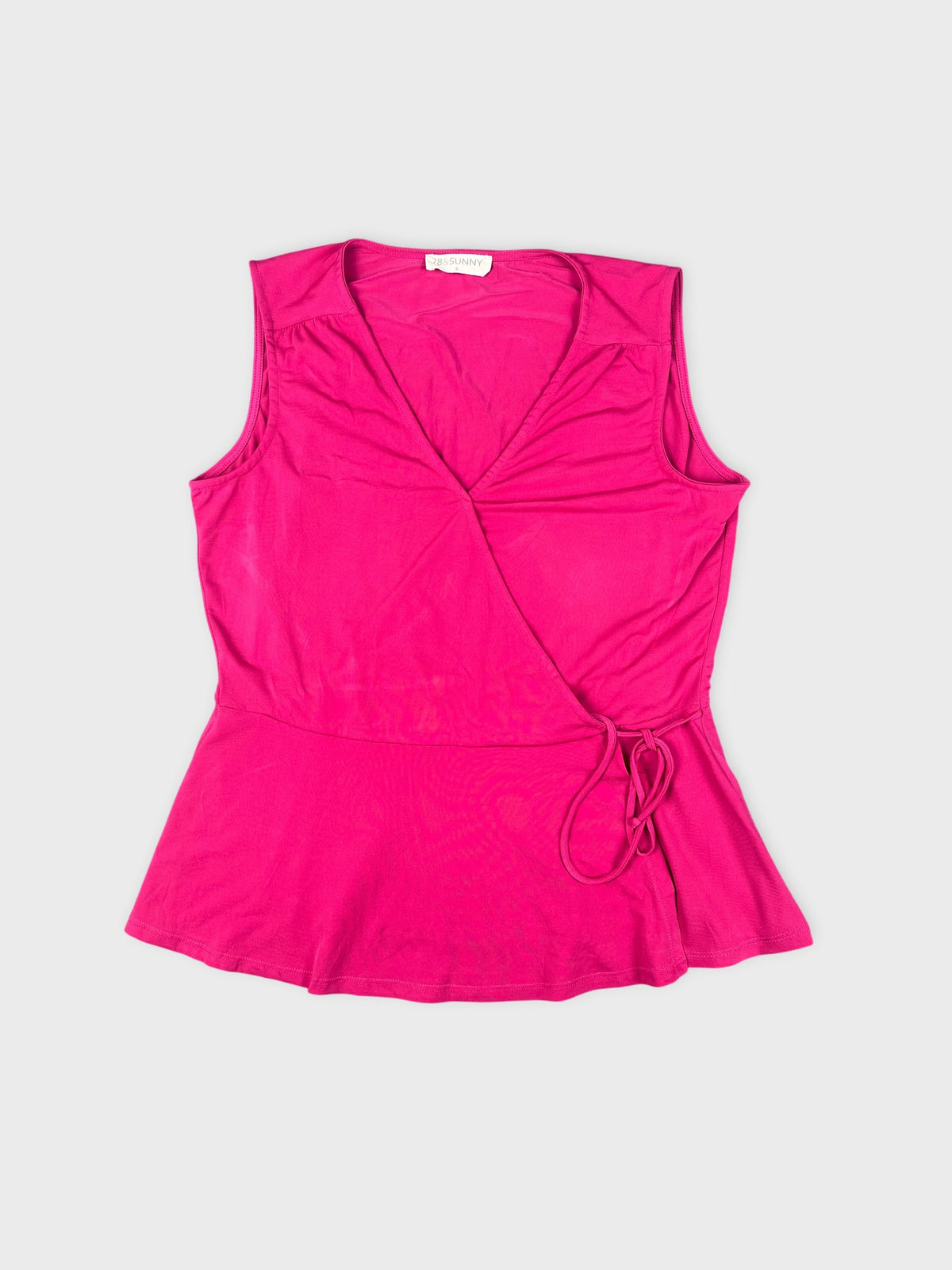 Detail view of a pink sleeveless top with a wrap design.