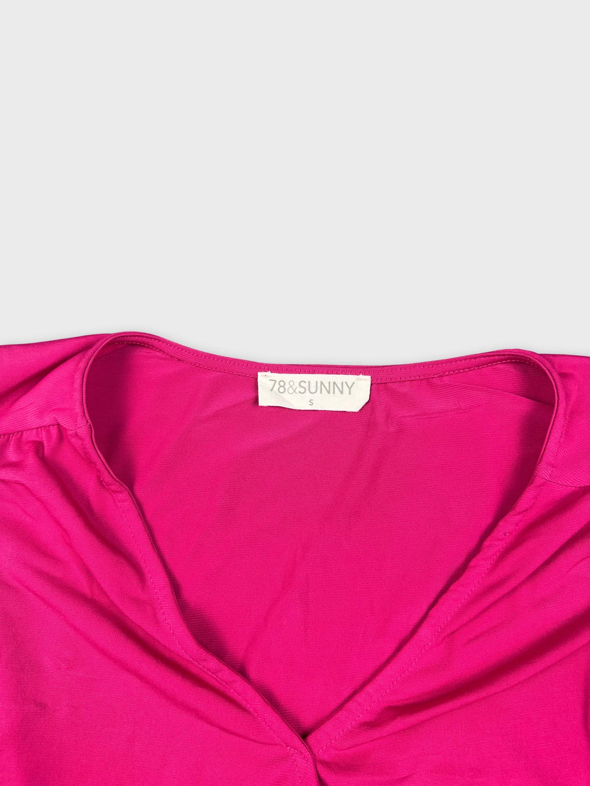 Detail view of a pink sleeveless top with a deep neckline.