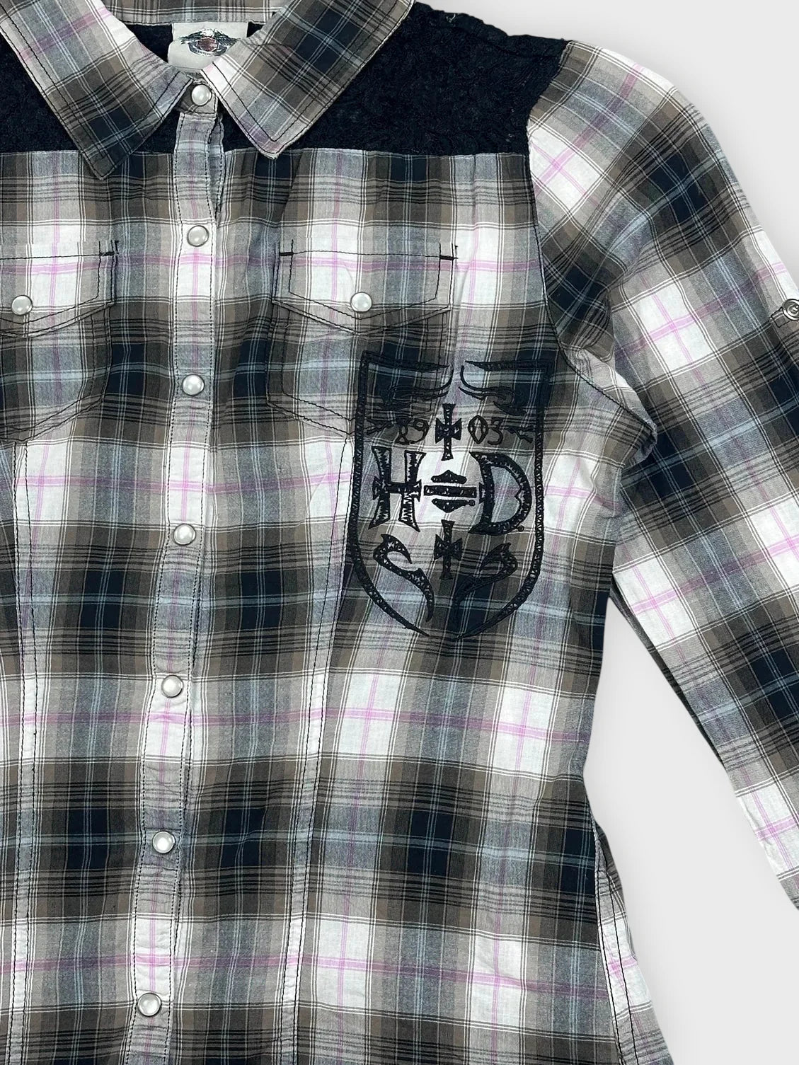 Detail view of plaid button-up shirt in black white and pink with chest pocket design.