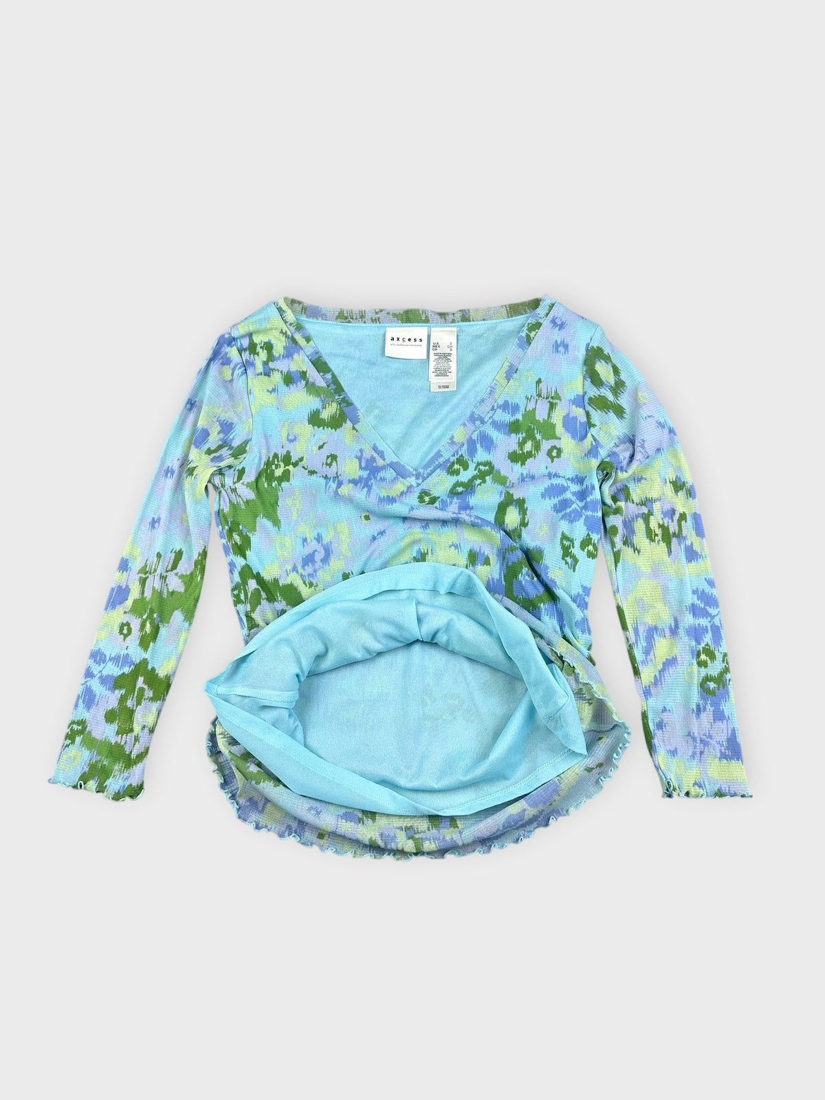 Detail view of a printed v-neck top in blue and green with flare hem.