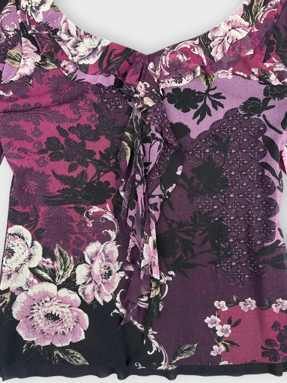 Detail view of a purple floral lace top with ruffled neckline.