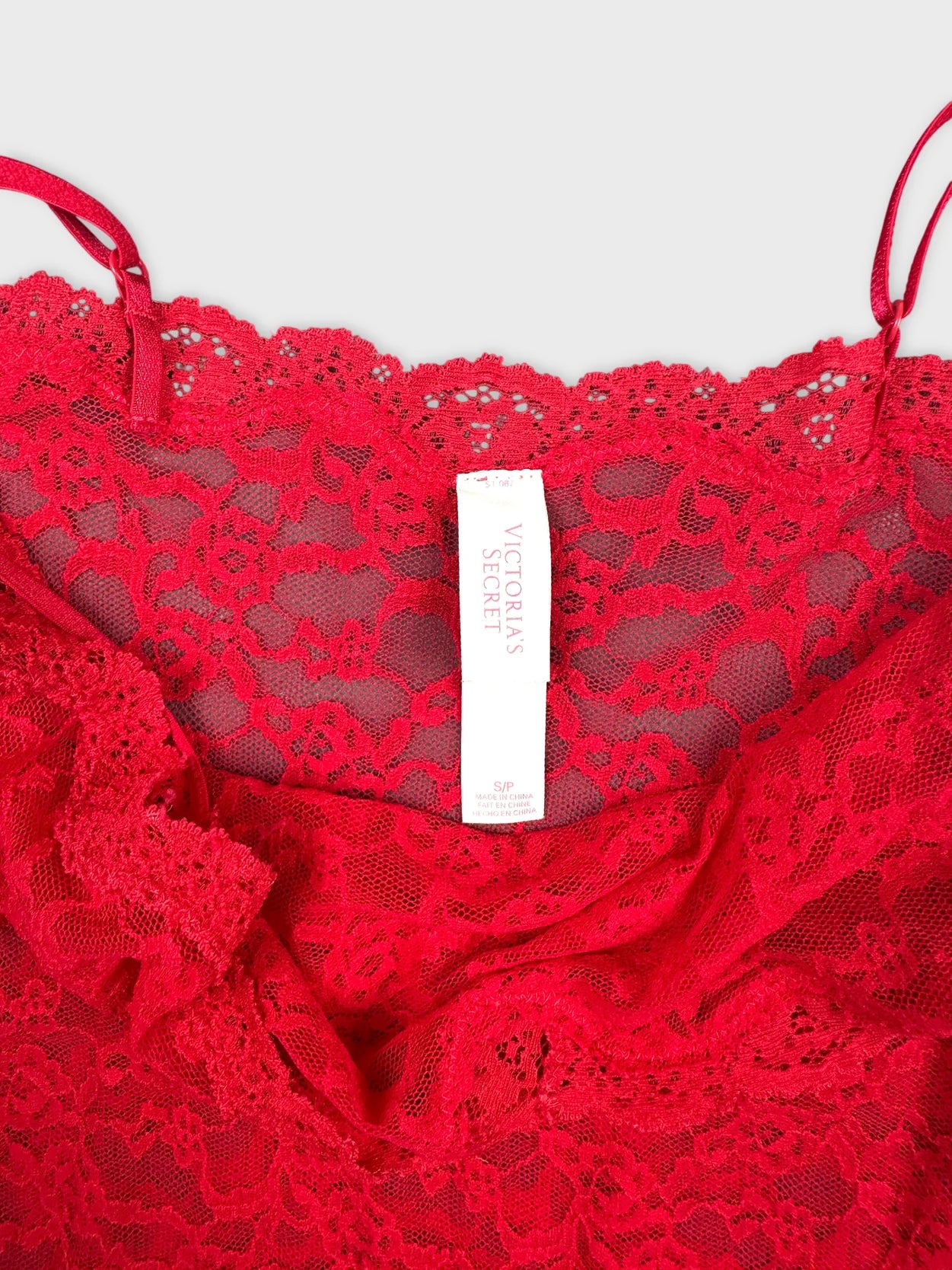 Detail view of a red lace cami top with a scalloped trim.
