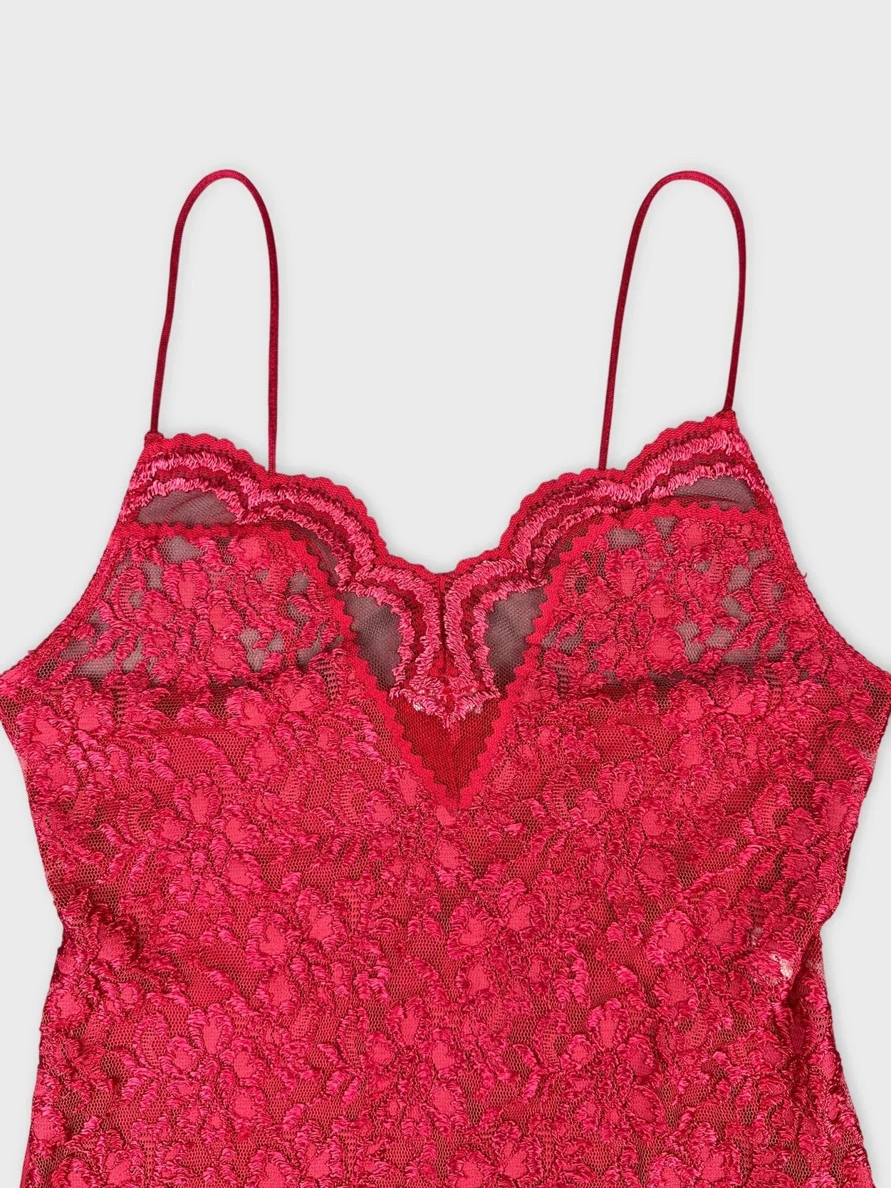 Red lace slip dress detail view featuring scalloped neckline and adjustable straps.