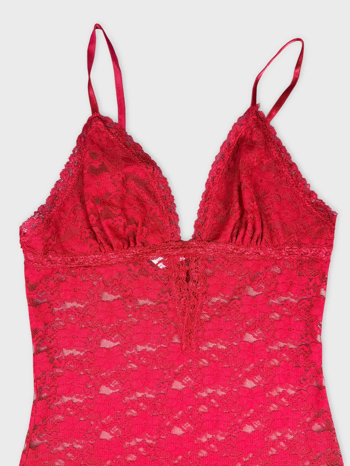 Detail view of a red lace top featuring delicate straps and sheer design.