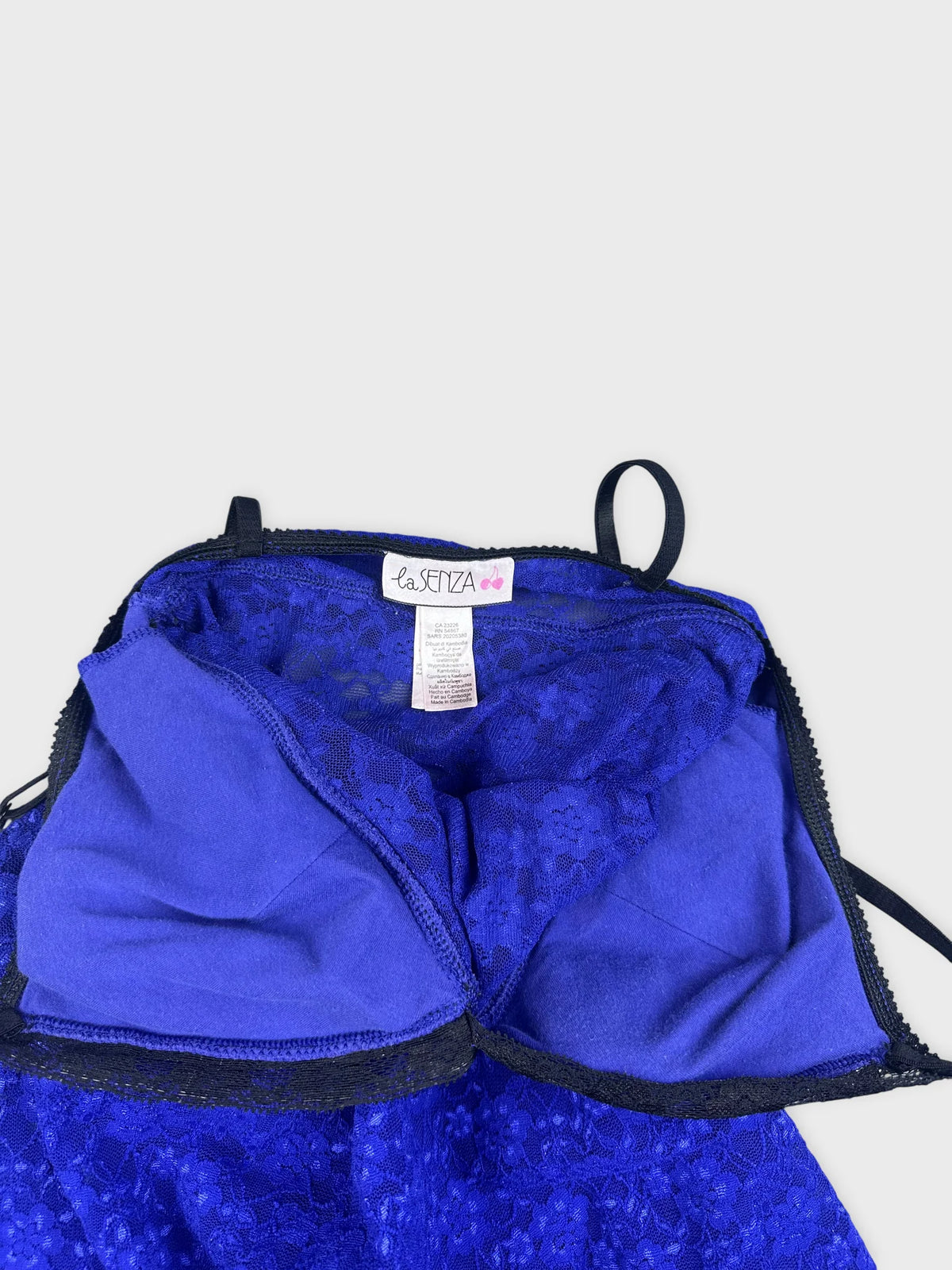 Detail view of a royal blue mini dress with black lace trim.