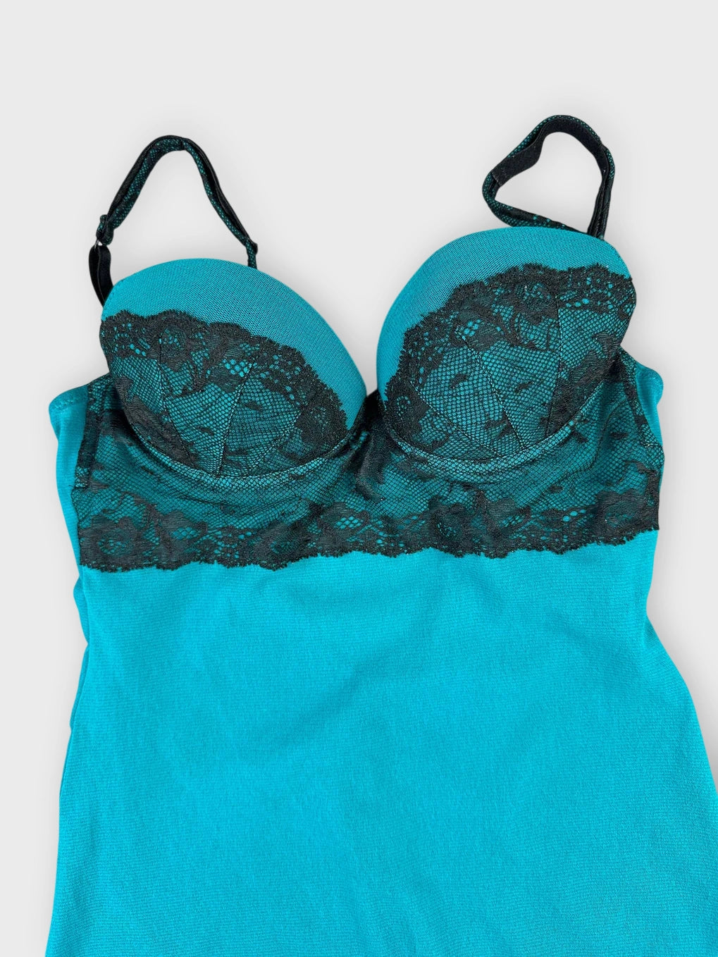 Detail view of sheer aqua lace top featuring black scalloped trim.