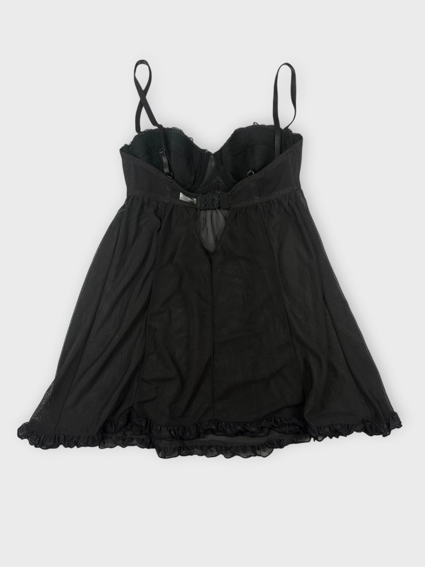 Back view of sheer black babydoll top with pink trim and ruffled hem.