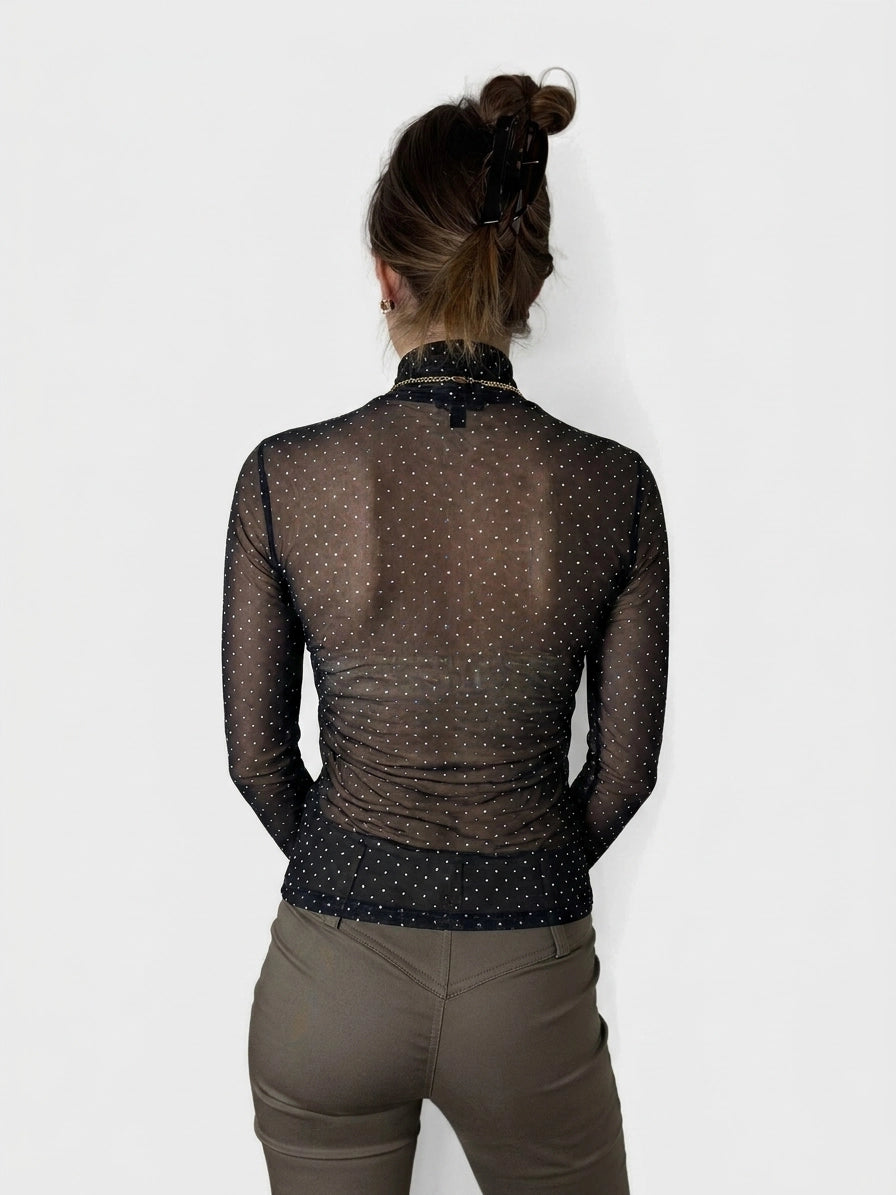 Back view of a sheer black long sleeve top with polka dots.