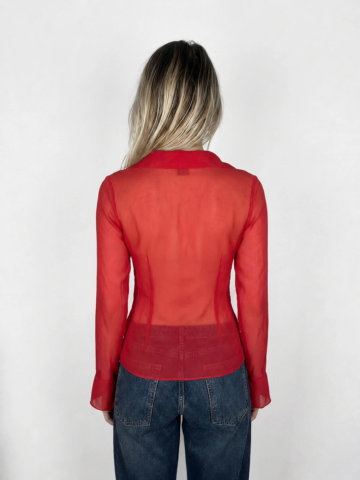 Back view of sheer red button-up top with tie detail.