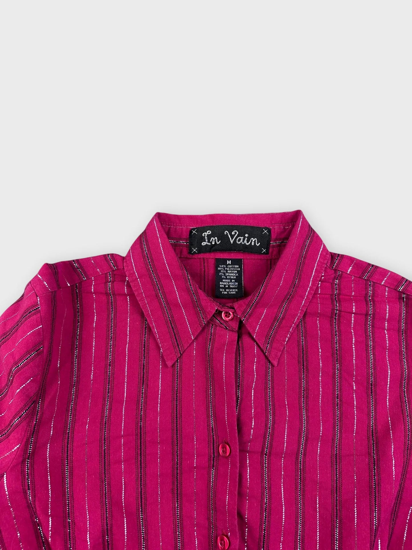 Detail view of a shimmering pink long sleeve shirt featuring silver vertical stripes.