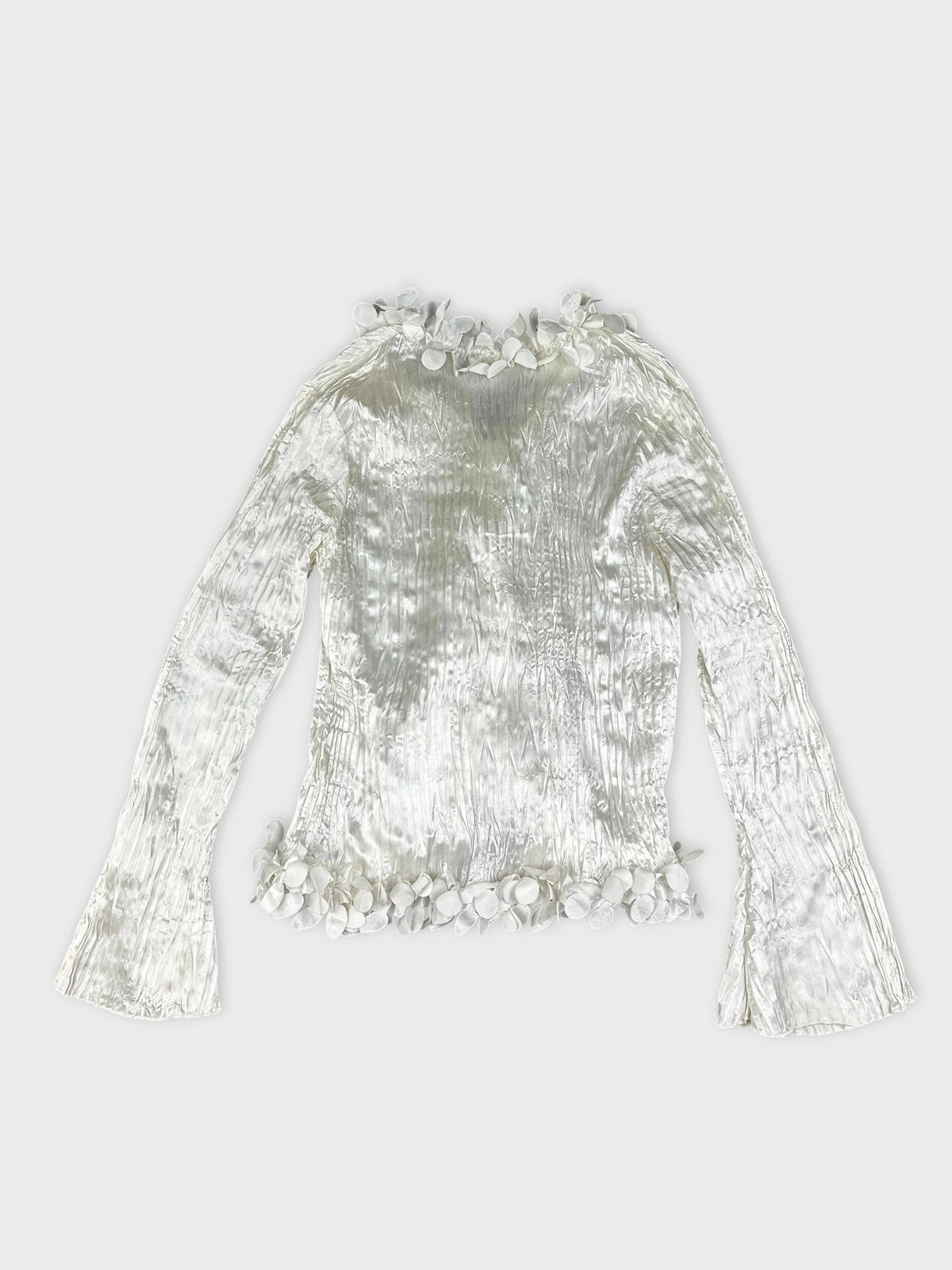 Back view of a shiny white long sleeve blouse with floral trim.