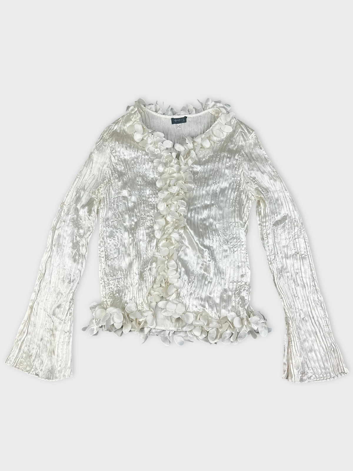 Front view of a shiny white long sleeve blouse with floral trim.