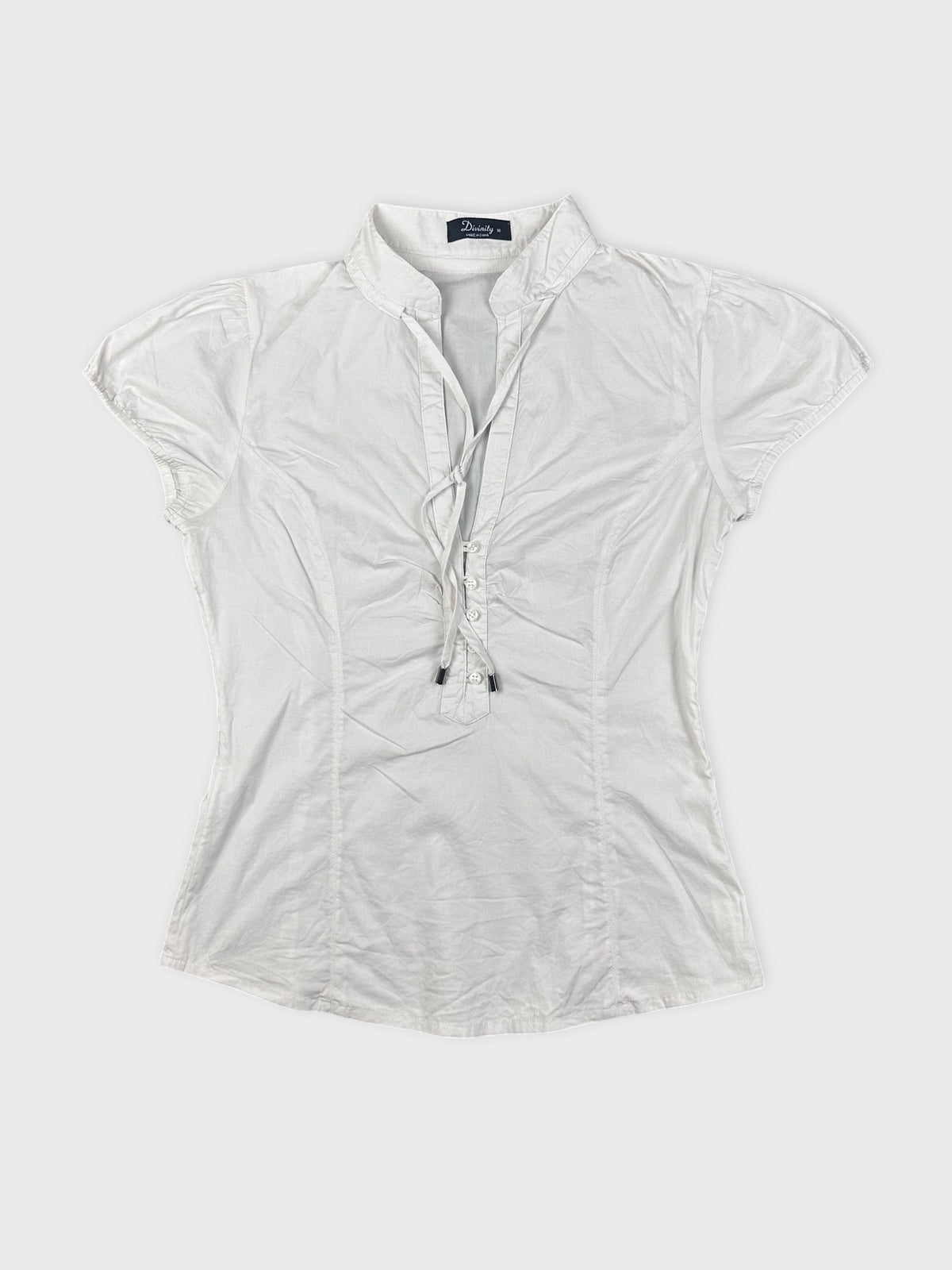 detail view of short-sleeve white blouse with button front and collar