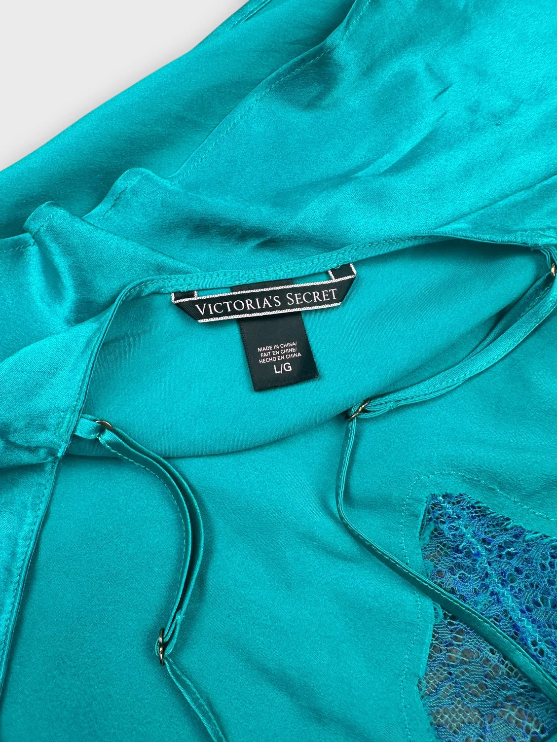 Detail view of aqua silk halter top featuring lace trim around the neckline.