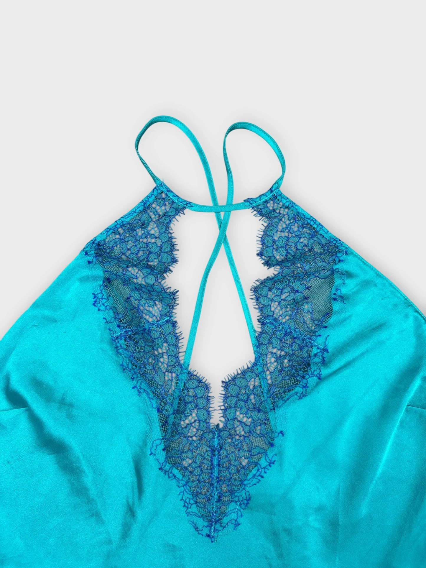 Detail view of aqua silk halter top featuring lace trim neckline.