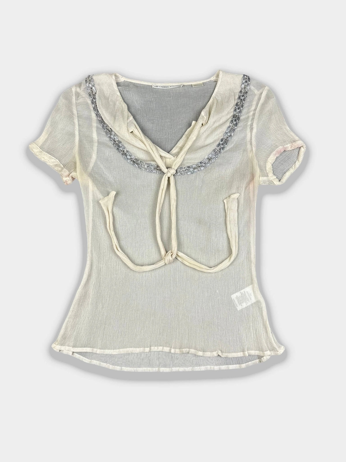 Front view of a silk tie-front top in cream with decorative neckline.