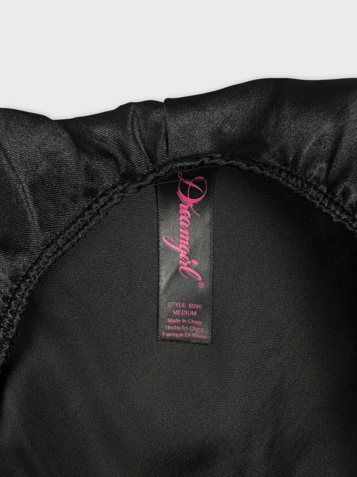 Detail view of a black halter top with adjustable straps and smooth fabric.