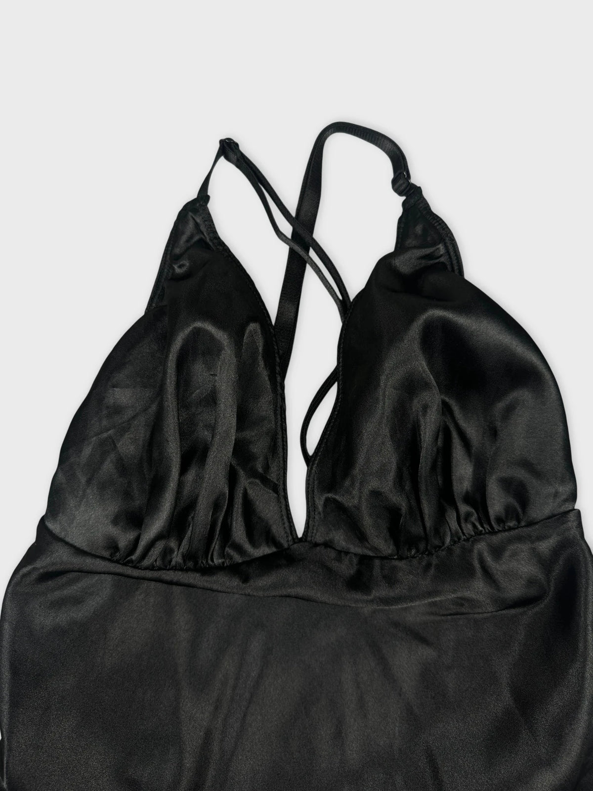 Silky black halter top detail view featuring V-neck and adjustable straps.
