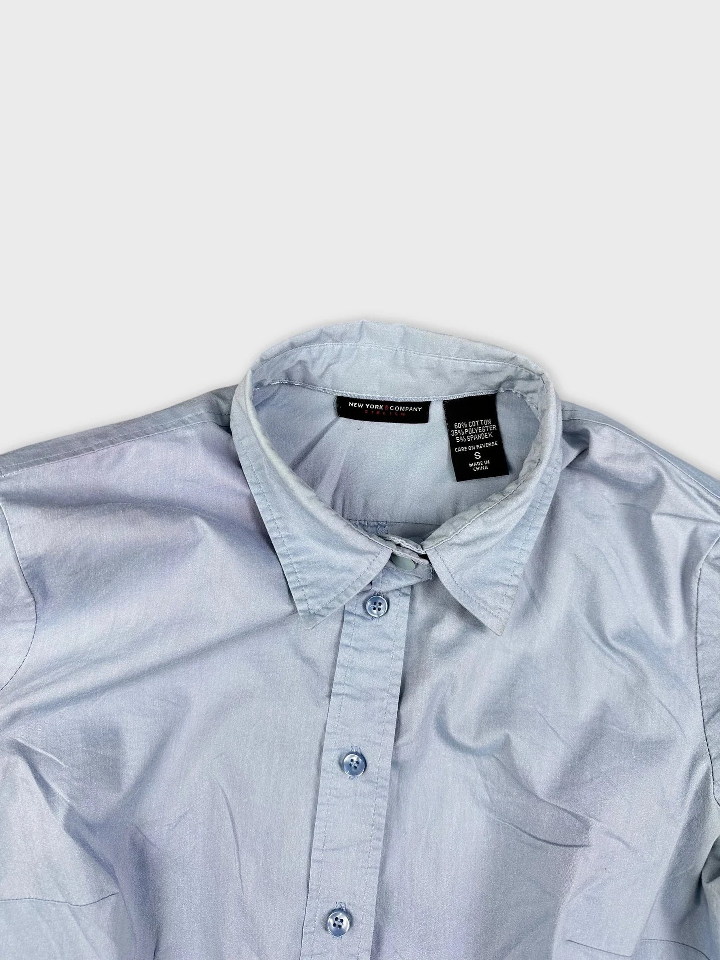 Detail view of a sky blue button up shirt featuring a classic collar and buttons.