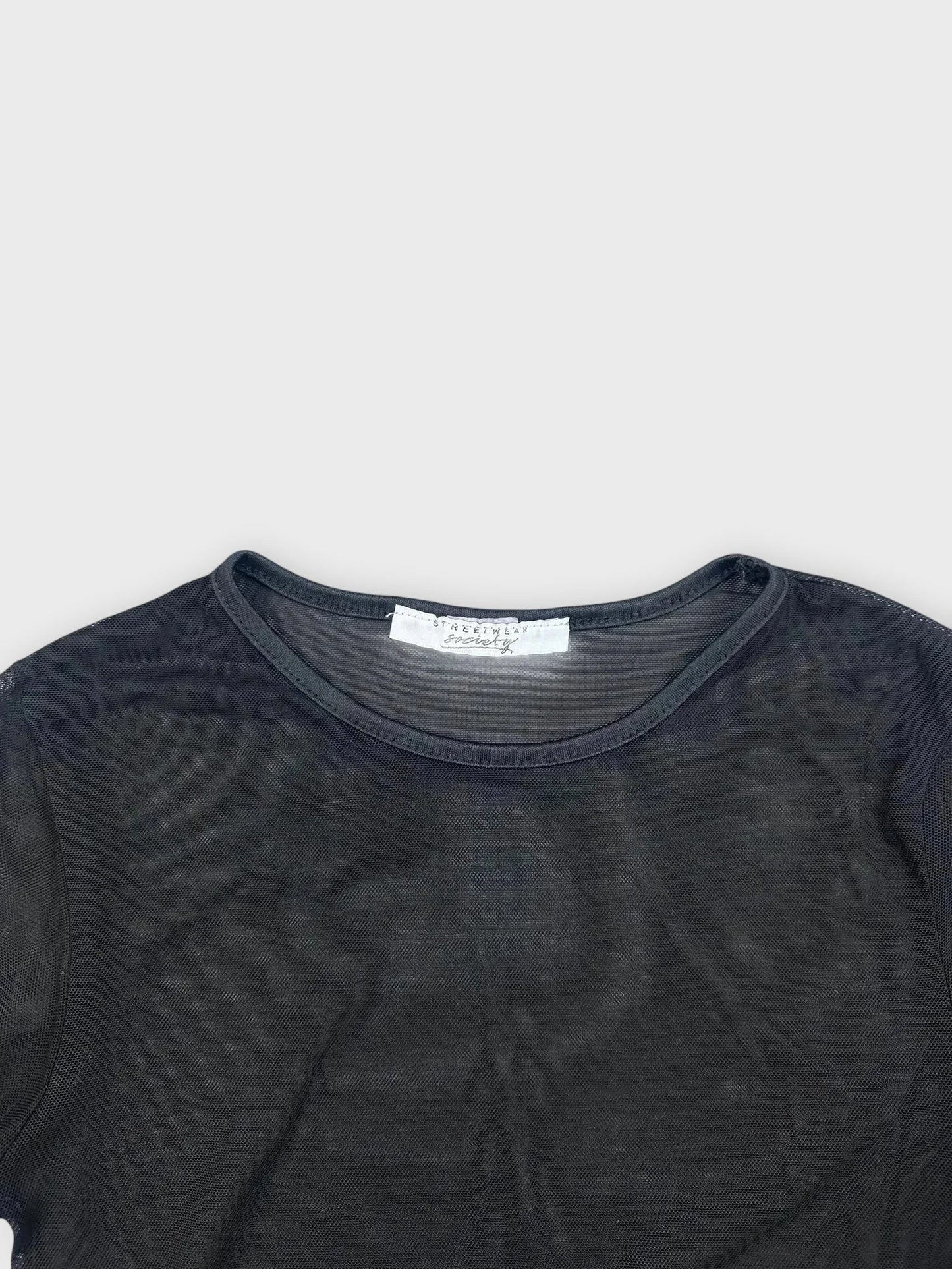 Detail view of a sheer black long-sleeve top featuring a round neck.