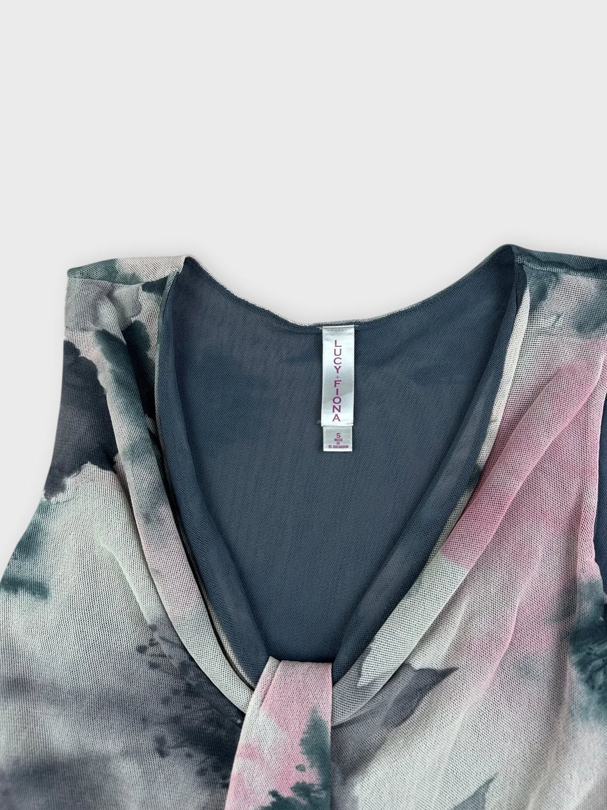 Detail view of a sleeveless floral top in soft pink and gray hues.