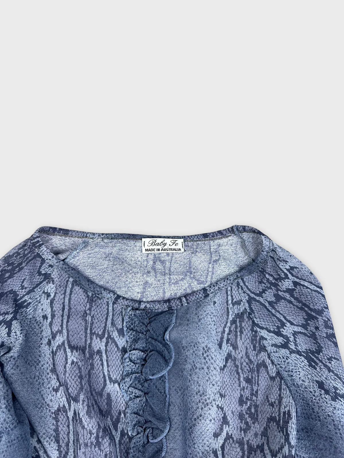 Snake print long-sleeve top in blue detail view with ruffled trim.