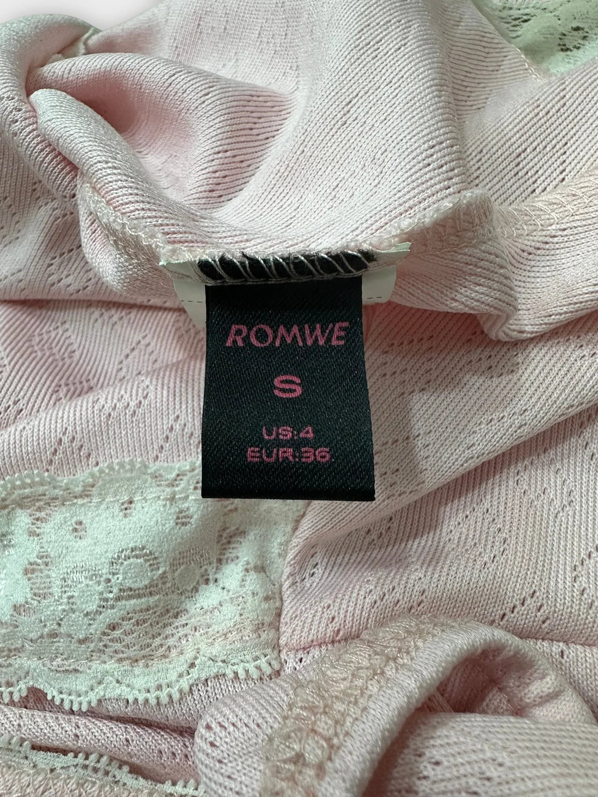Detail view of soft pink lace-trim blouse featuring a bow detail.