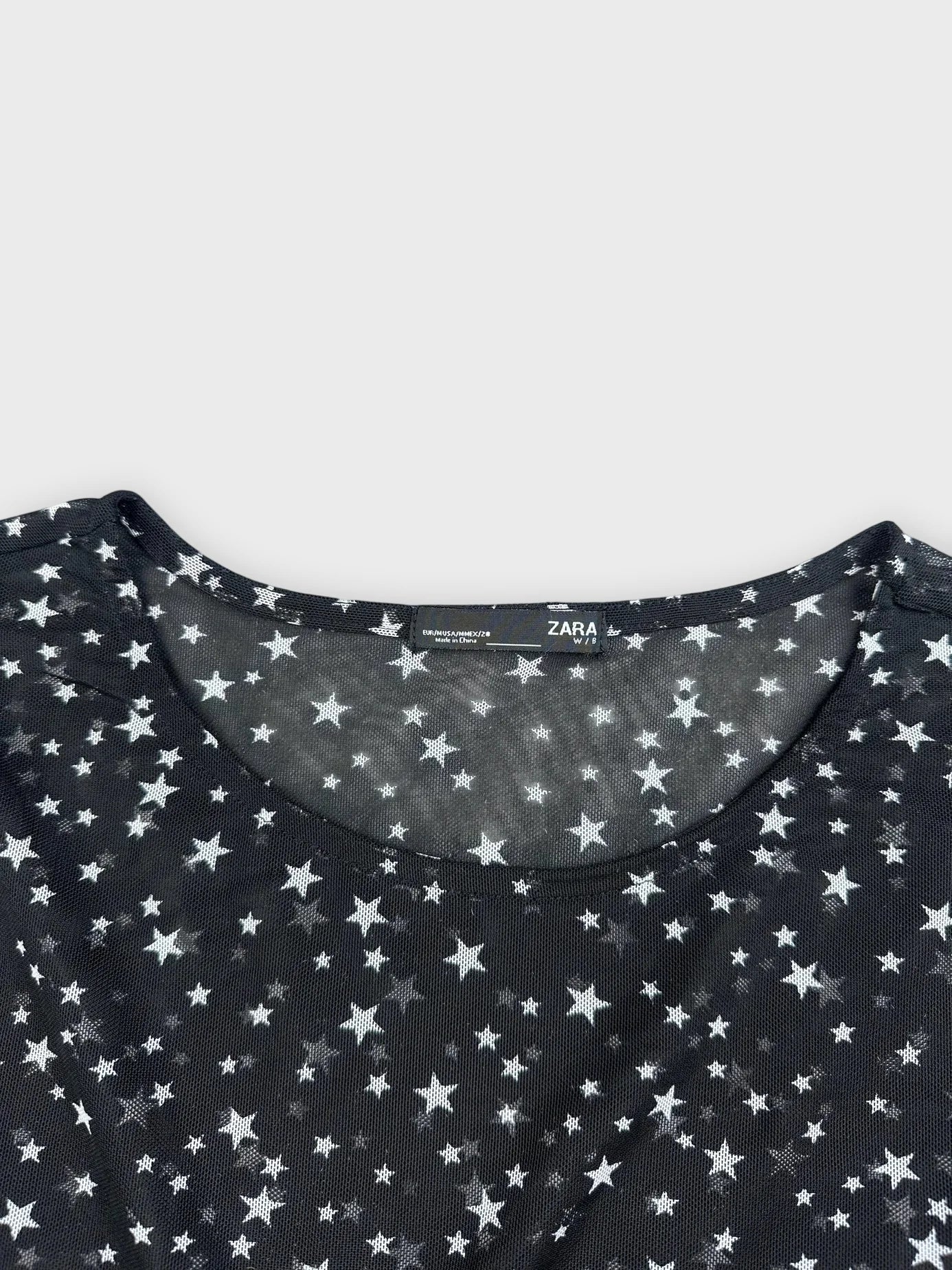 Detail view of black long sleeve top with star pattern.