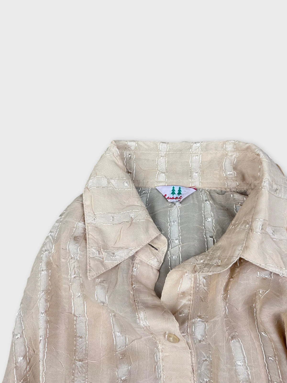 Detail view of a striped blouse in soft beige with subtle texture.