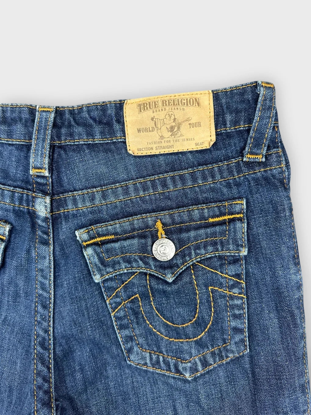 Detail view of blue denim shorts featuring back pockets and yellow stitching.