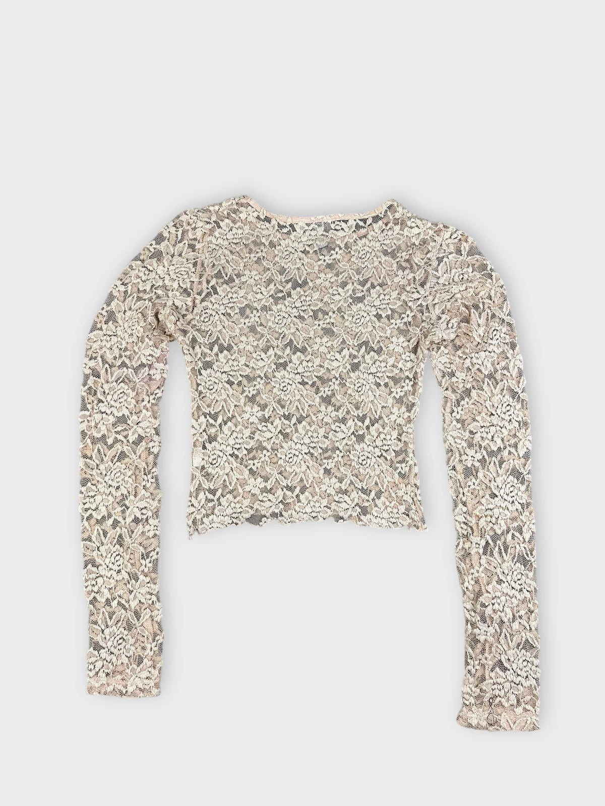 Back view of a vintage cream lace crop top with long sleeves.
