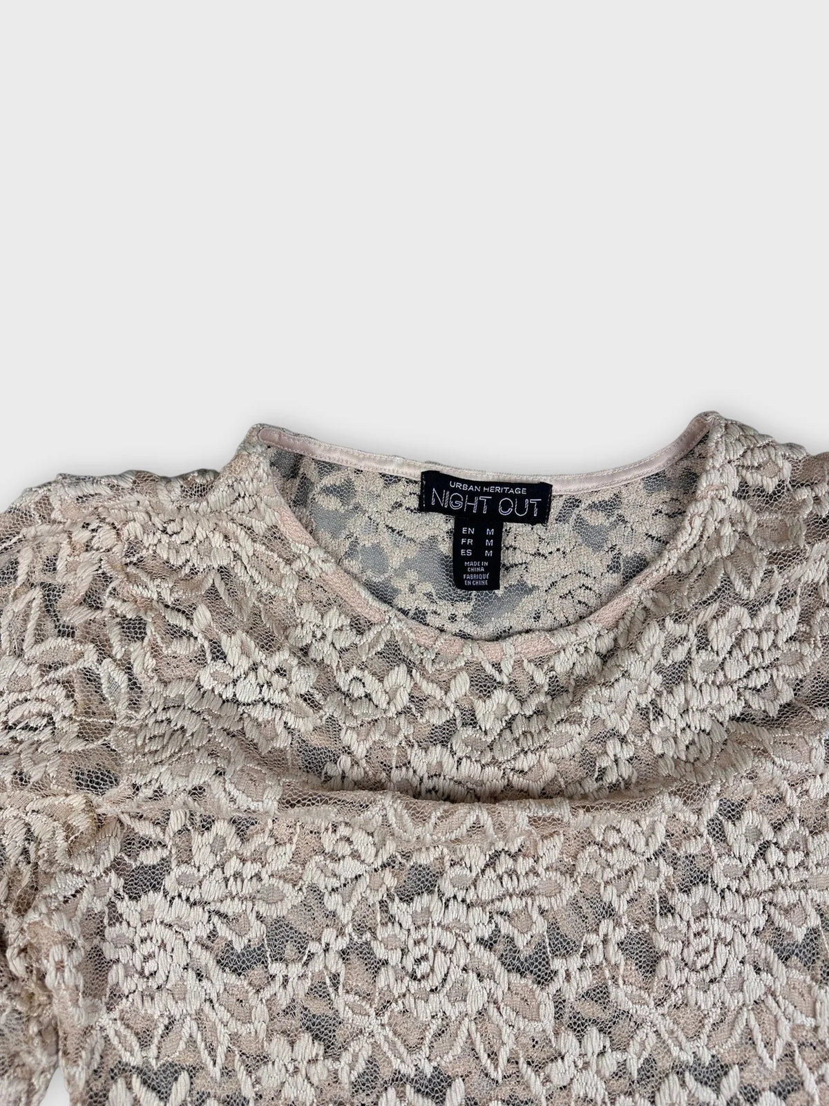Detail view of vintage cream lace crop top showcasing floral pattern and round neckline.