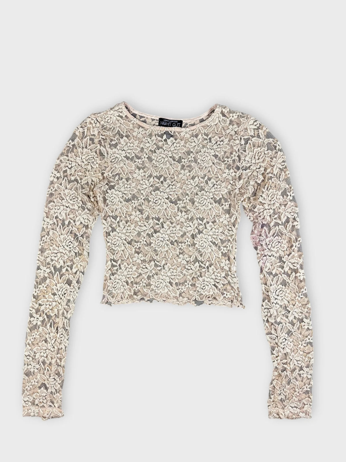 Detail view of vintage cream lace crop top with floral pattern.