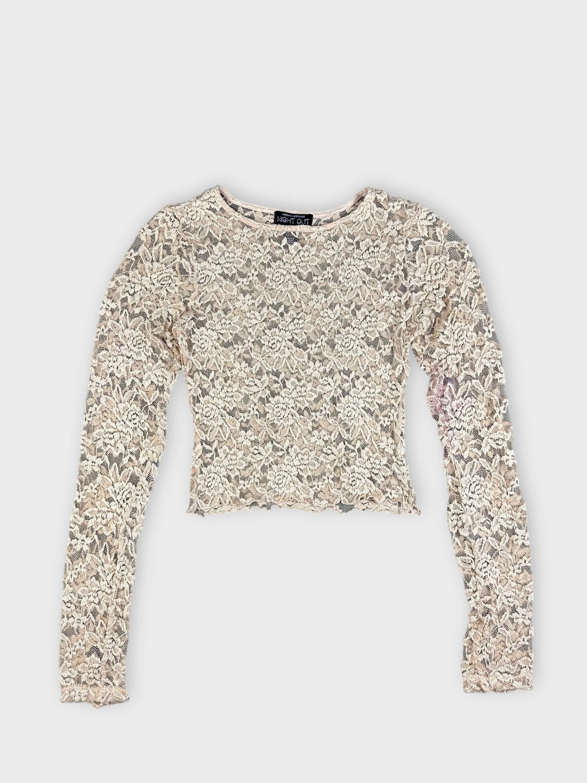Front view of cream lace crop top with floral pattern and long sleeves.