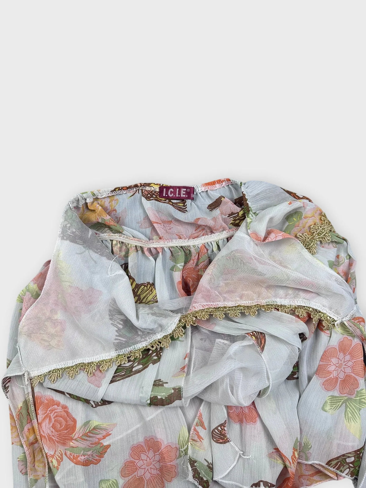 Detail view of a vintage floral butterfly cami in light gray with golden trim.