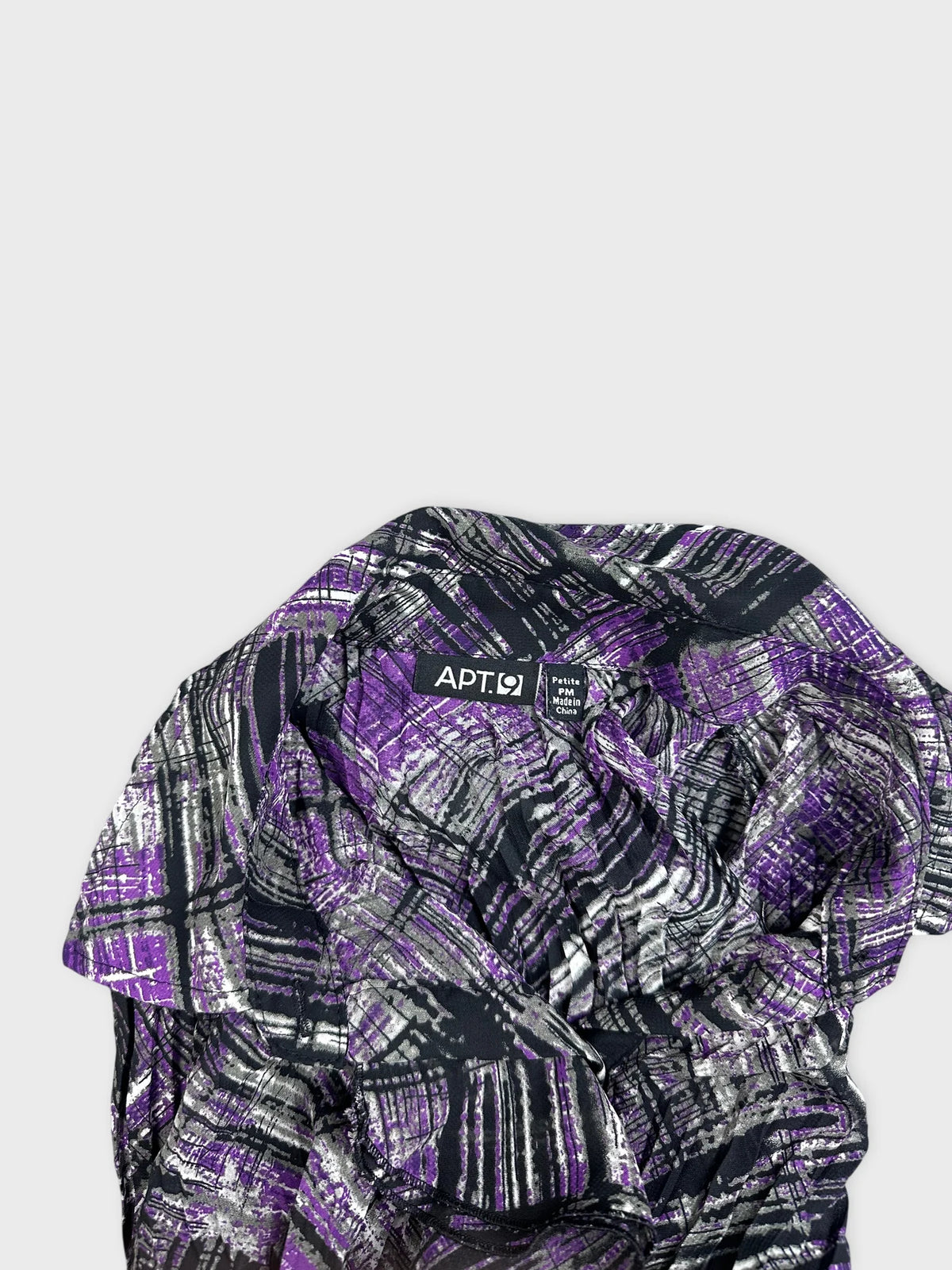 Detail view of a violet plaid long-sleeve shirt with contrasting patterns.