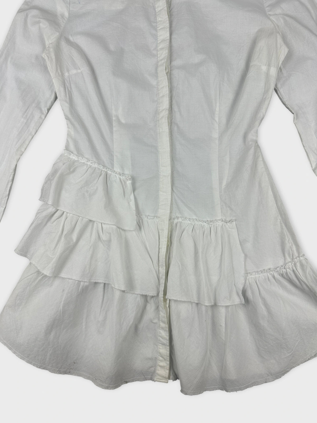 Detail view of a white cotton peplum button-up shirt with layered ruffle trim.