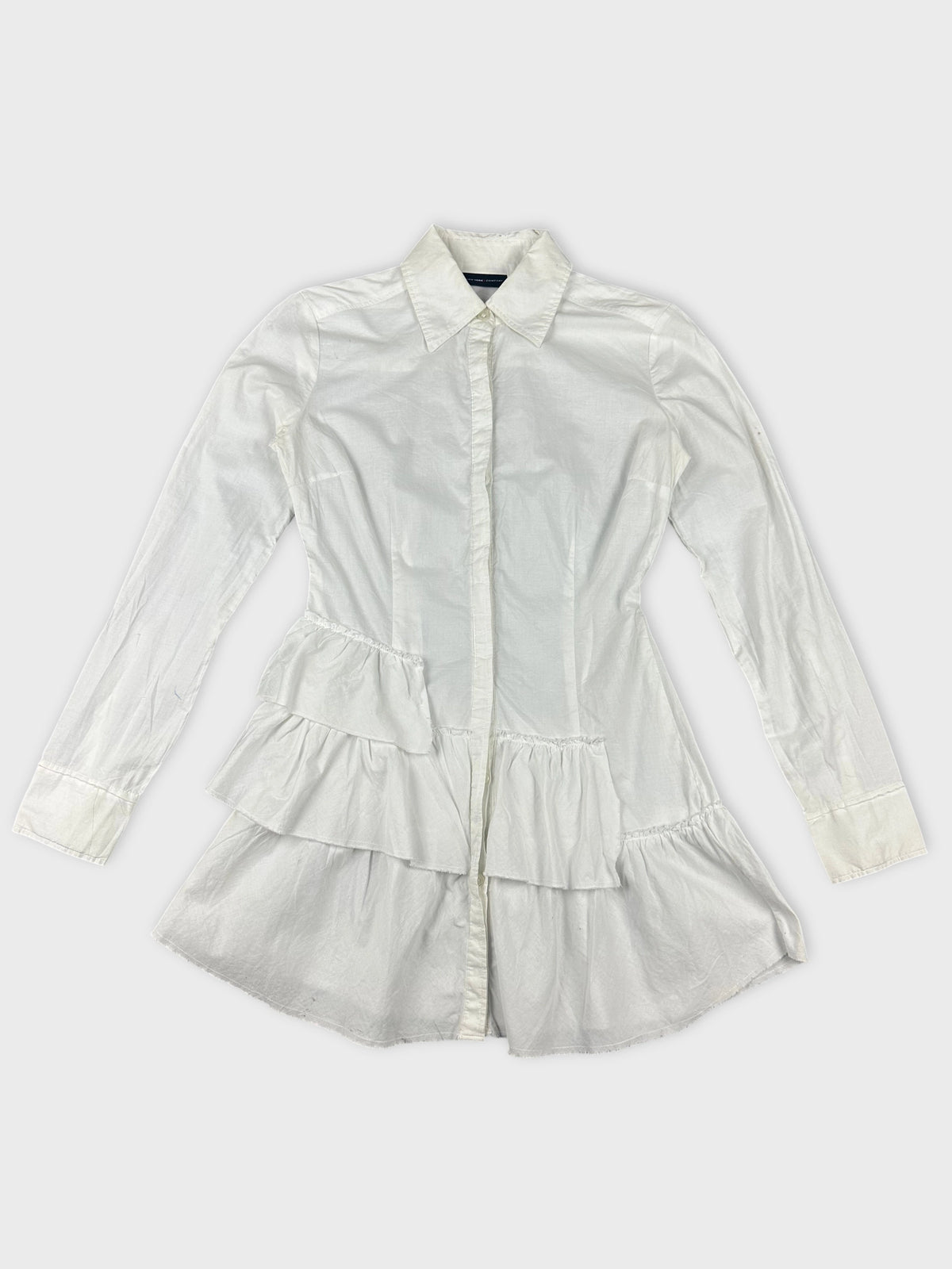 Detail view of white cotton peplum button-up shirt with tiered ruffles.