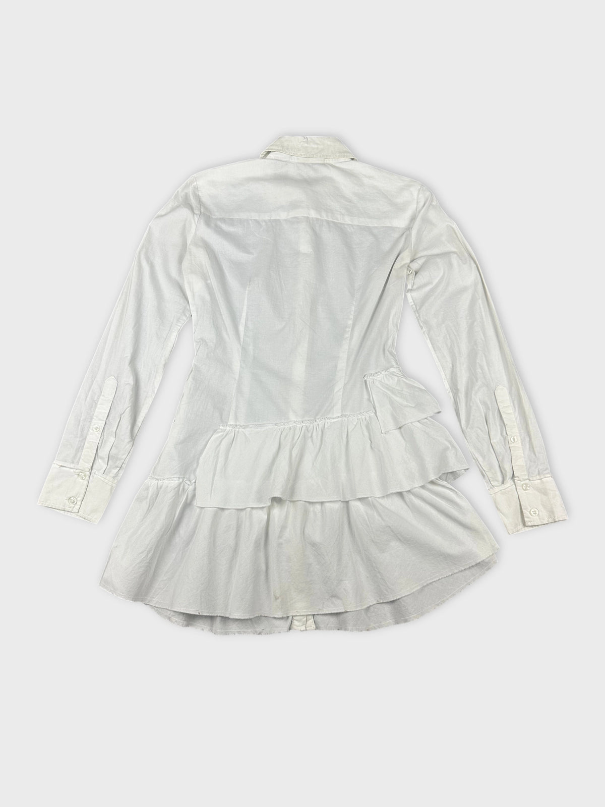 Detail view of a white cotton peplum button-up shirt with layered ruffles.