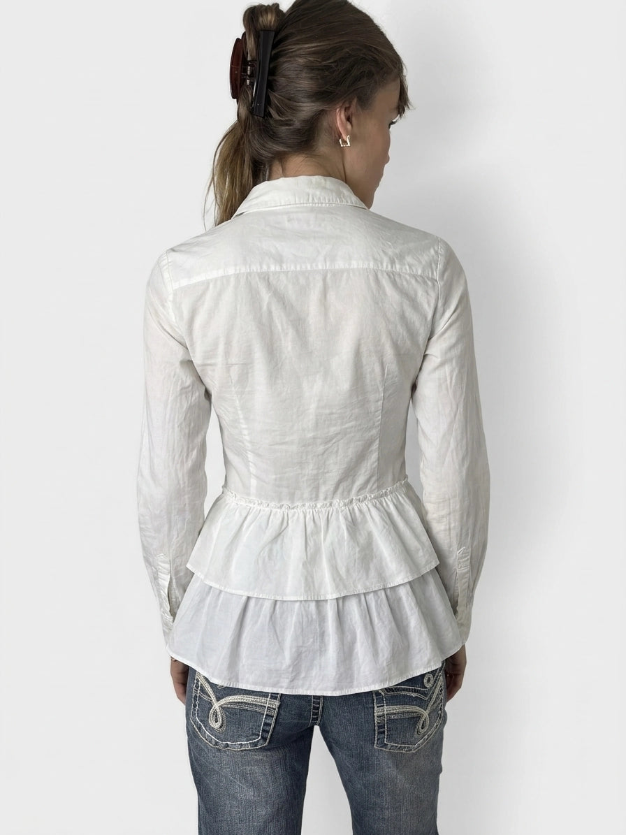 Back view of a white cotton peplum button-up shirt featuring a layered hem.