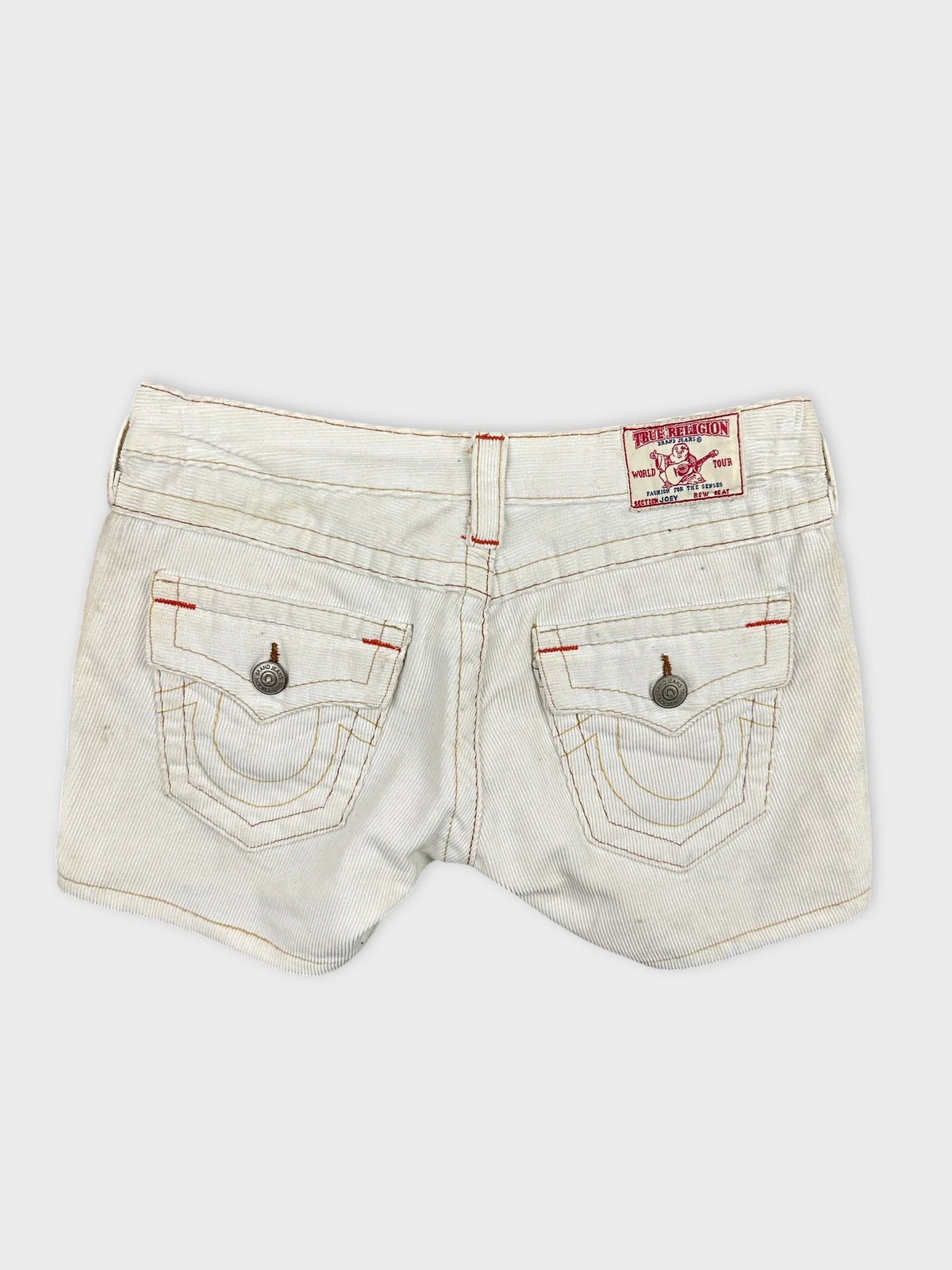Back view of white denim shorts with edgy stitching and decorative pockets.
